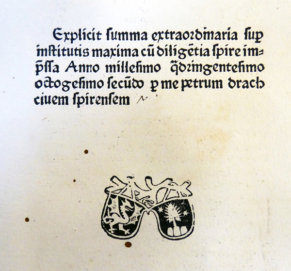 Der abgebildete Seitenausschnitt stammt aus der Inkunabel „Summa super Codice et Institutis“ des Autors Portius Azo, die 1482 in der Offizin Peter Drachs in Speyer gedruckt wurde. Am Ende des Haupttextes findet sich die Druckermarke Peter Drachs sowie ein Kolophon, der Auskunft über den Inhalt, den Druckort, das Jahr und den Druckherrn gibt. Heidelberg UB, J 1150 B Folio INC (GW 3144).